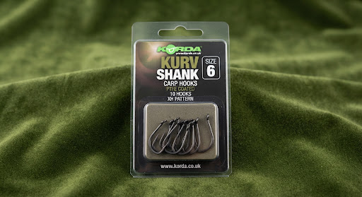 Korda Kurv Shank carp hooks in original tackle packaging resting on green velvet background.
