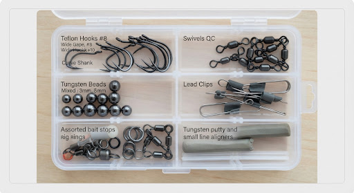 Organized tackle box compartments with precision sharp Teflon coated carp hooks, swivels, lead clips and tungsten beads.