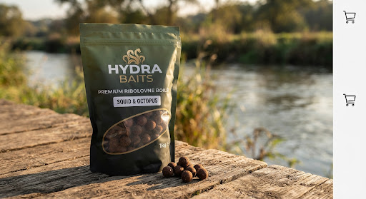 Pakiranje premium ribolovnih boila Hydra Baits na drvenoj podlozi uz rijeku, prirodno toplo svjetlo, tamnozeleni detalji pakiranja, makro fotografija ribolovnog mamca visoke rezolucije.